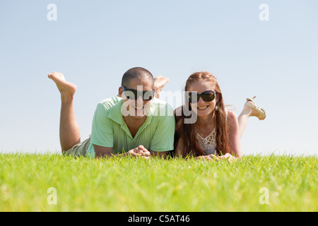 Happy couple together laying down on a green grass field Stock Photo