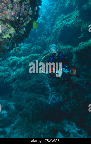 A female photographer swimming through a swim-through in Little Cayman. Stock Photo