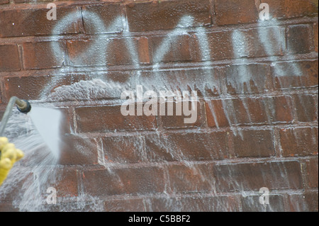 Council worker cleaning graffiti off of a wall in England. Stock Photo