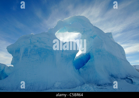 Sun shines through hole in iceberg arch set in sea ice in Ross Sea Antarctica Stock Photo