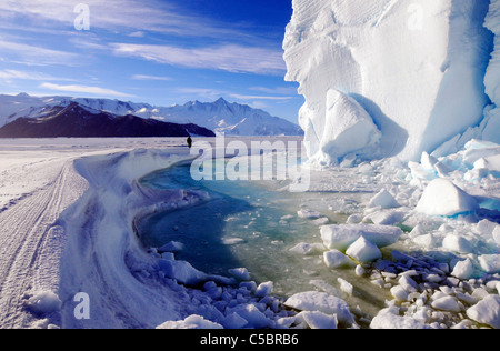 Mount Herschel with person, large ice berg and marine algae in pool near Cape Hallett northern Ross Sea Antarctica Stock Photo