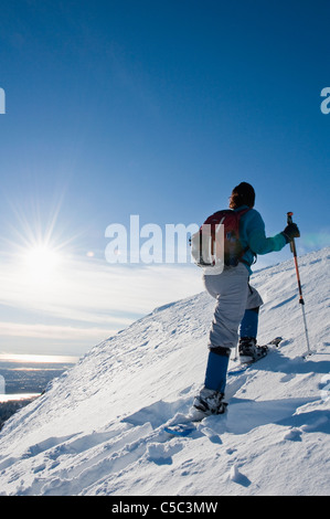 Hispanic woman snowshoeing up hill Stock Photo