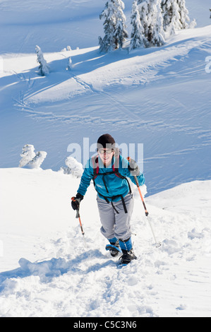 Hispanic woman snowshoeing up hill Stock Photo