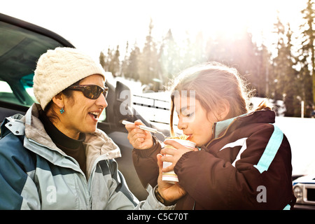 Mother and daughter eating lunch in snow Stock Photo