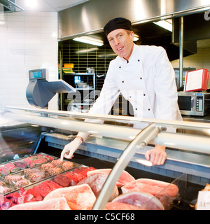 A butcher at a fresh meat counter or deli in a store Stock Photo