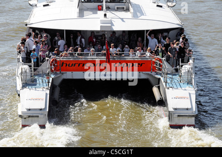 Crowd of people passengers travelling on stern of Thames Clipper catamaran boat a public transport river bus service on London famous river England UK Stock Photo