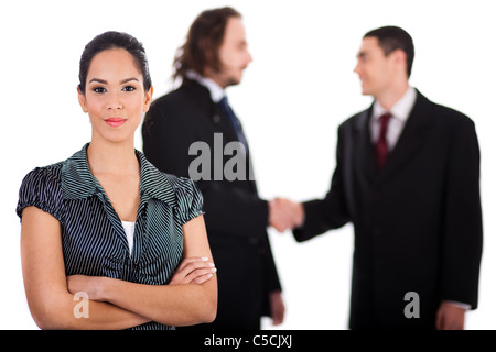 Smiling business women in focus with two business colleague welcoming each other behind her out of focus Stock Photo