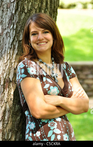 A attractive Hispanic girl leans against a tree. Stock Photo