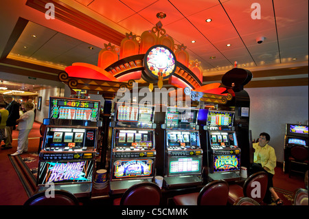 Passengers playing at slot machines in the Empire Casino, Queen Mary 2 Cruise Ship. Stock Photo