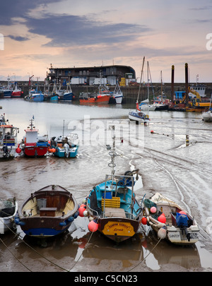 Fishing boats moored in Bridlington Harbour at low tide with The Fish Dock visible in the background Bridlington East Yorkshire Stock Photo