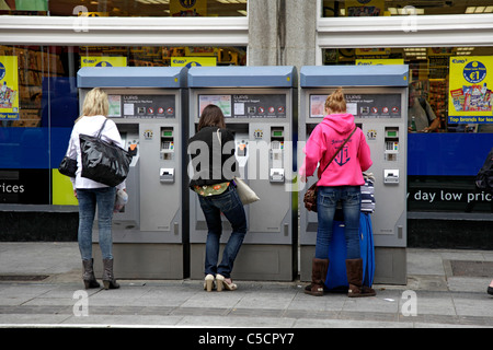 Three young women buying tickets for the LUAS tram system in Abbey Street, central Dublin Stock Photo