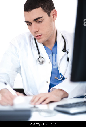 Handsome doctor making notes from the computer at his desk Stock Photo
