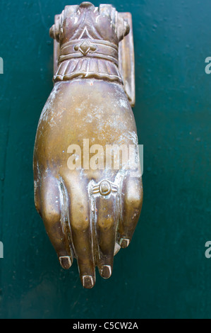 Hand-shaped knocker on old wooden door in Greece Stock Photo