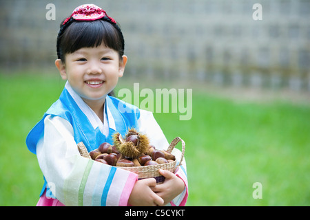 girl in hanbok hugging basket which was full of chestnuts Stock Photo