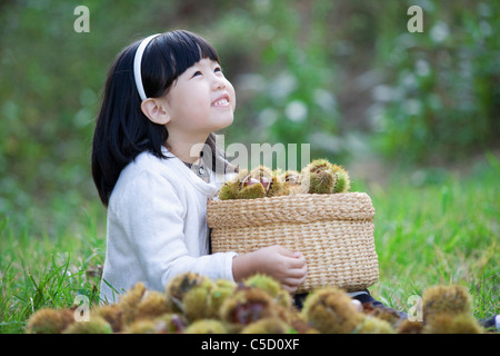 girl hugging basket which was full of chestnuts Stock Photo
