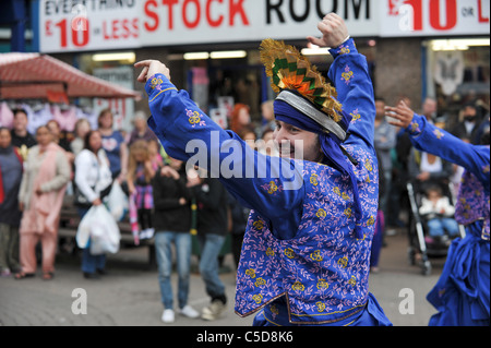 Colourful Bhangra dancers in traditional dress performing in front of a crowd of shoppers in West Bromwich High Street Stock Photo