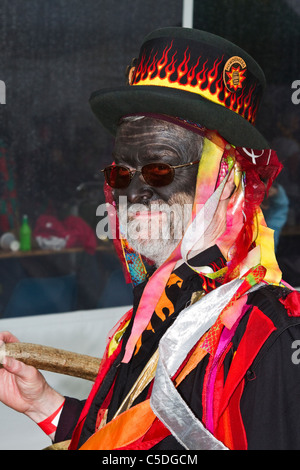 Foxs Border Morris Dancers in bright tattered clothing. Detail and People, Performing at Tutbury Castle Weekend of Dance  Derbyshire, UK. Foxs Morris perform an interpretation of the 'Border' Morris dances collected in Worcestershire, Herefordshire and Shropshire. Certain aspects of the side's kit reflect some theories as to the origins, meanings & symbolisms, on the tradition's past as a form of winter begging, e.g., the wearing of bells- to add noise and rhythm, dancing with sticks- to add noise & look threatening, and blackened the faces- to disguise dancers and musicians. Stock Photo