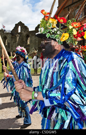 Exmoor Border Mixed Morris Dancers, black-faced, wearing long flowing torn old rags, clothing made from wide bolts of blue and white material, clothes & dancing celebration, outdoors event, street dancer, costumed dancers, performance, folk entertainers, multi colored, music festival, musicians, popular, performing traditional leisure activity at Tutbury Castle Weekend of Dance  Derbyshire, UK. Stock Photo