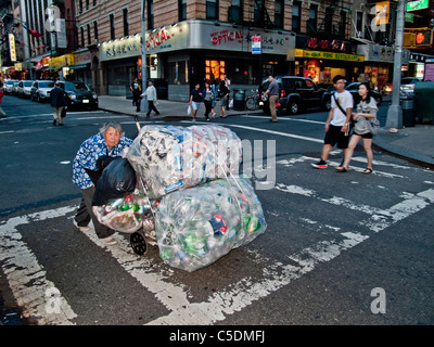A poor elderly Chinese woman collects cans and bottles for deposit money in New York City's Chinatown on the lower east side. Stock Photo