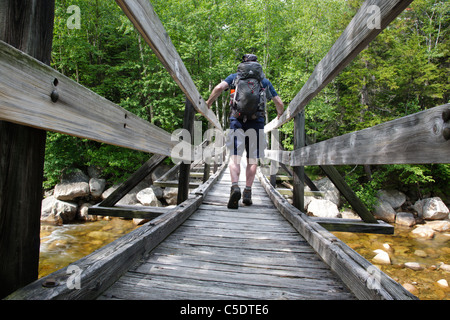 Pemigewasset Wilderness - A hiker on wooden footbridge, which crosses the East Branch of the Pemigewasset River in New Hampshire. Stock Photo