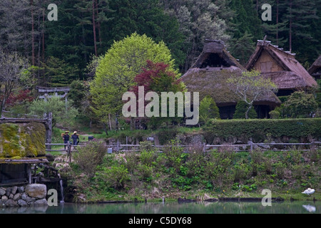 Two workers walk past traditional Japanese farm houses preserved at Hida no Sato folk village outside of Takayama. Stock Photo