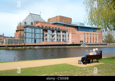 Four Old Age Pensioners or Elderly Retired Sit on a Park Bench Opposite the Royal Shakespeare Theatre at Stratford-upon-Avon Warwickshire England Stock Photo