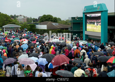 Crowds watch the big screen on Aorangi Terrace in the rain during the 2011 Wimbledon Tennis Championships Stock Photo