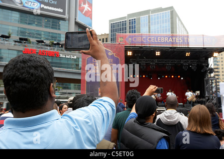 man taking photos and video with a tablet computer at an outdoor event toronto ontario canada Stock Photo