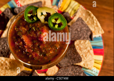 Homemade Salsa with blue and plain corn chips, sliced Jalapeños. Festive Mexican theme. Stock Photo