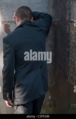 Depressed businessman man standing against the wall Stock Photo