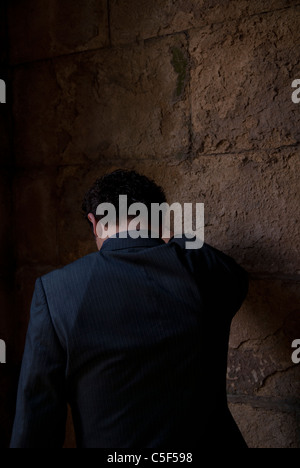 Depression. An depressed man leaning against the wall hit by a sunlight ...