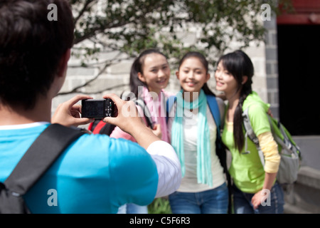 Young Man Taking a Photo of Three Friends Stock Photo