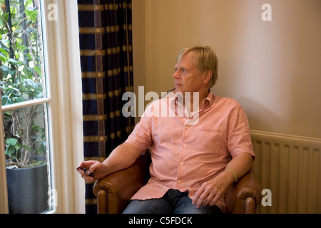 Mature man Looking out Window from Armchair Stock Photo