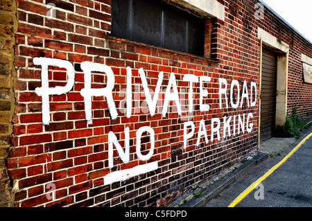 Hand painted 'Private Road  No Parking' sign on brick wall Stock Photo