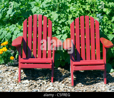 two adirondack chairs in a row at the edge of long lake