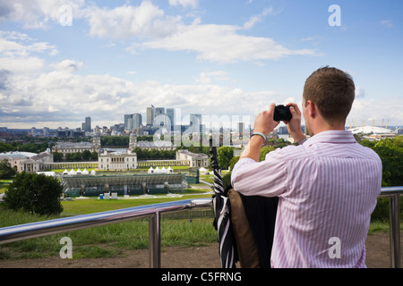 Man photographing view to Canary Wharf from the Observatory using a compact digital camera. Greenwich Park, London, England, UK Stock Photo