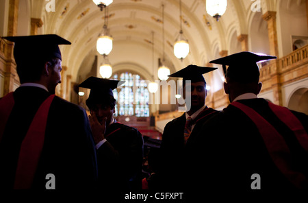 Four male graduates await the degree ceremony in the Great Hall of University of Birmingham, England, UK