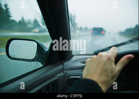 A first person perspective of driving on a freeway in the rain. Stock Photo