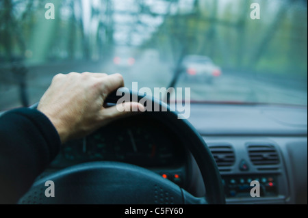A first person perspective of driving a car on a highway over a bridge in the rain. Stock Photo