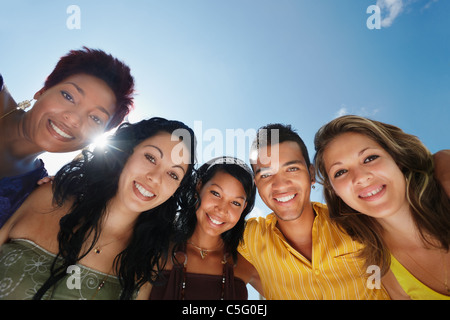 group of five young people looking at camera and smiling with sky in background. Low angle view, copy space Stock Photo