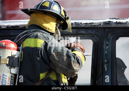 Fire fighter putting out a car fire Stock Photo