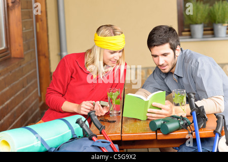 Tramping young couple backpack relax sitting by wooden cottage Stock Photo