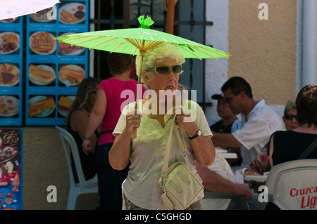 Elderly Woman Sheltering From The Sun With A Parasol On A Hot Day Stock Photo