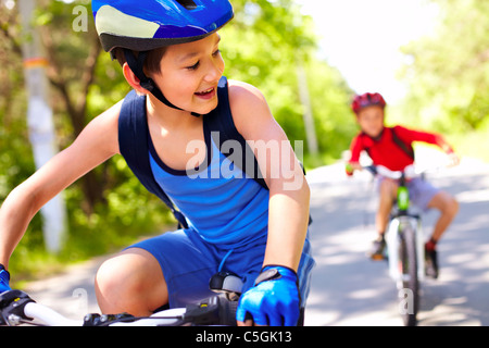 Two little boys riding bikes one after another