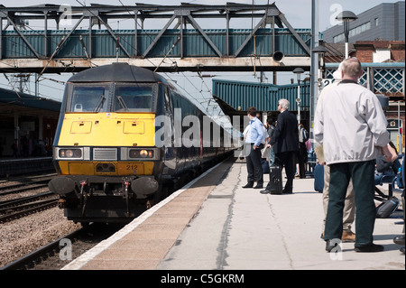 Passengers waiting to board an East Coast train at a railway station in England. Stock Photo