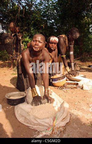 Surma women and girl grinding corn west of Omo River Ethiopia Stock Photo