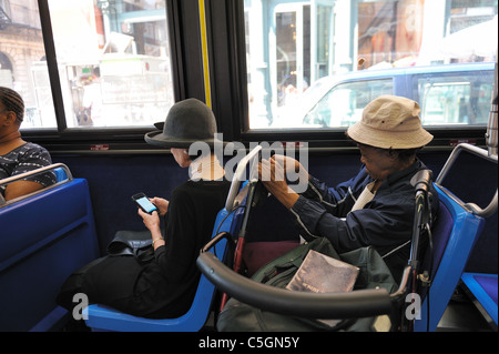 An expensively dressed woman and a poor one with a walker and a Bible sitting near each other on a Manhattan bus. July 20, 2011