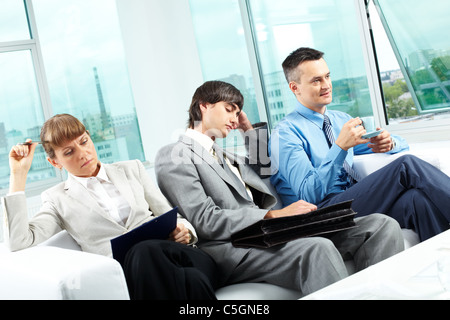 Three office workers sitting on sofa after hard workday Stock Photo