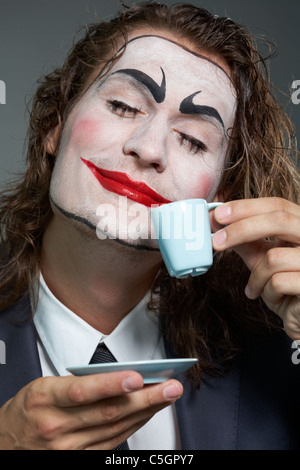 Portrait of businessman with painted face drinking coffee Stock Photo