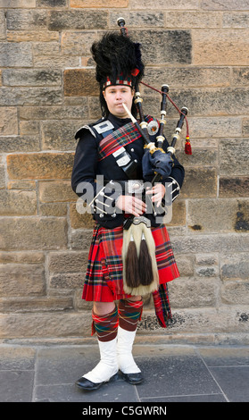 Scottish Piper in traditional dress playing the bagpipes outside Edinburgh Castle, Old Town, Edinburgh, Scotland, UK Stock Photo